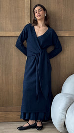 navy blue wrap dress with a tie-front detail, paired with a layered hemline and black ballet flats