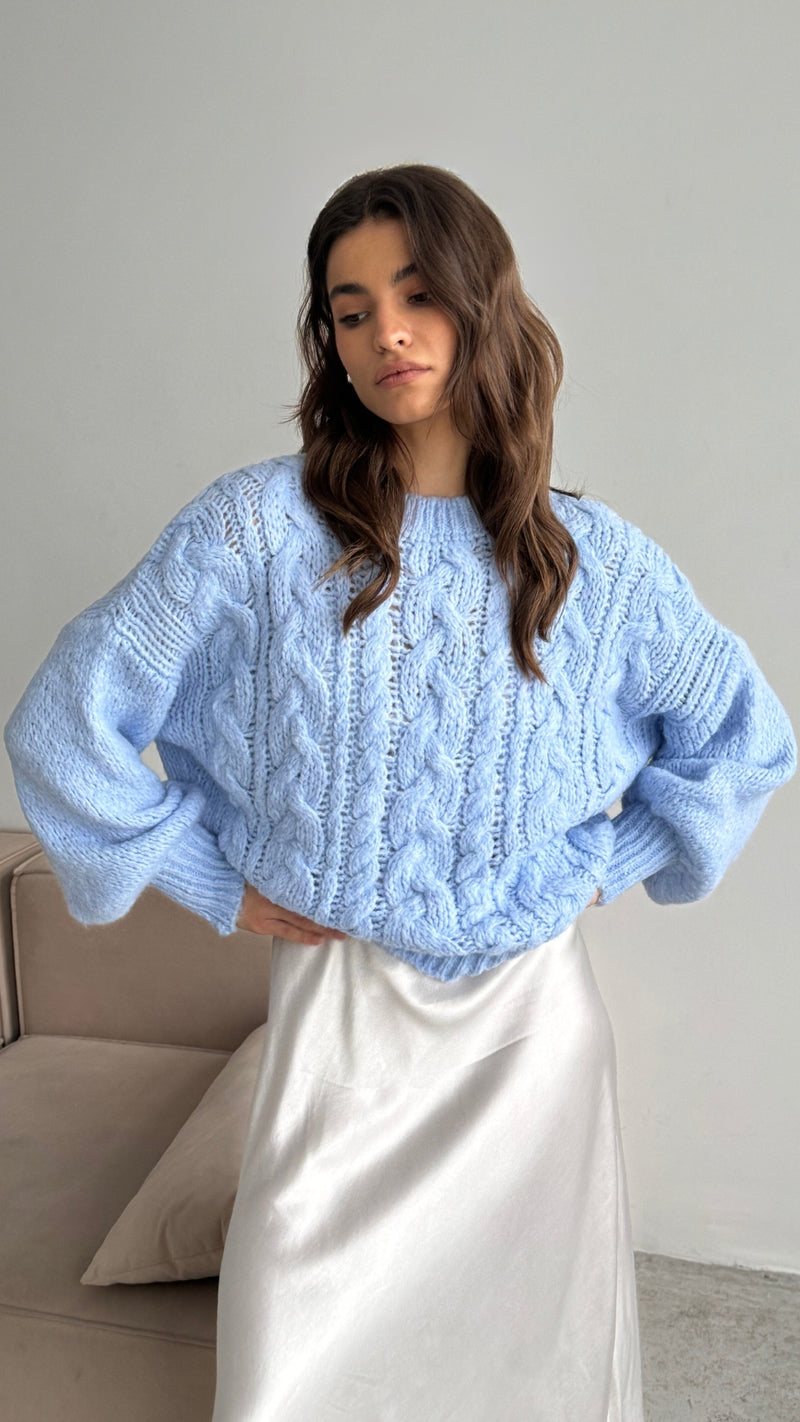 light blue cable-knit sweater paired with a silky white midi skirt