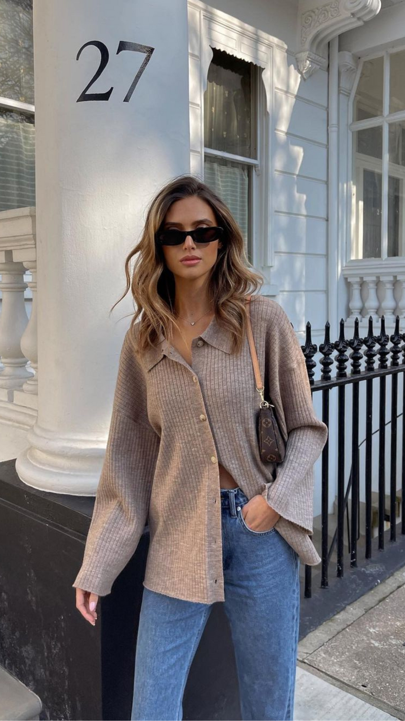 beige ribbed button-up shirt, with the top button undone, paired with blue jeans.