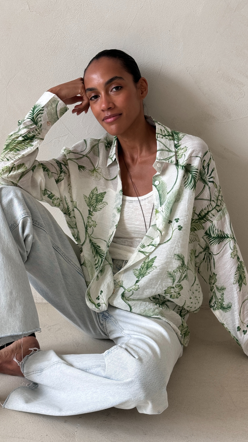 green botanical printed button-up shirt over a white top, paired with light wash jeans