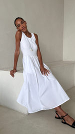 sleeveless white midi dress with a fitted bodice and flared skirt, styled with black strappy sandals and a minimalist pendant necklace