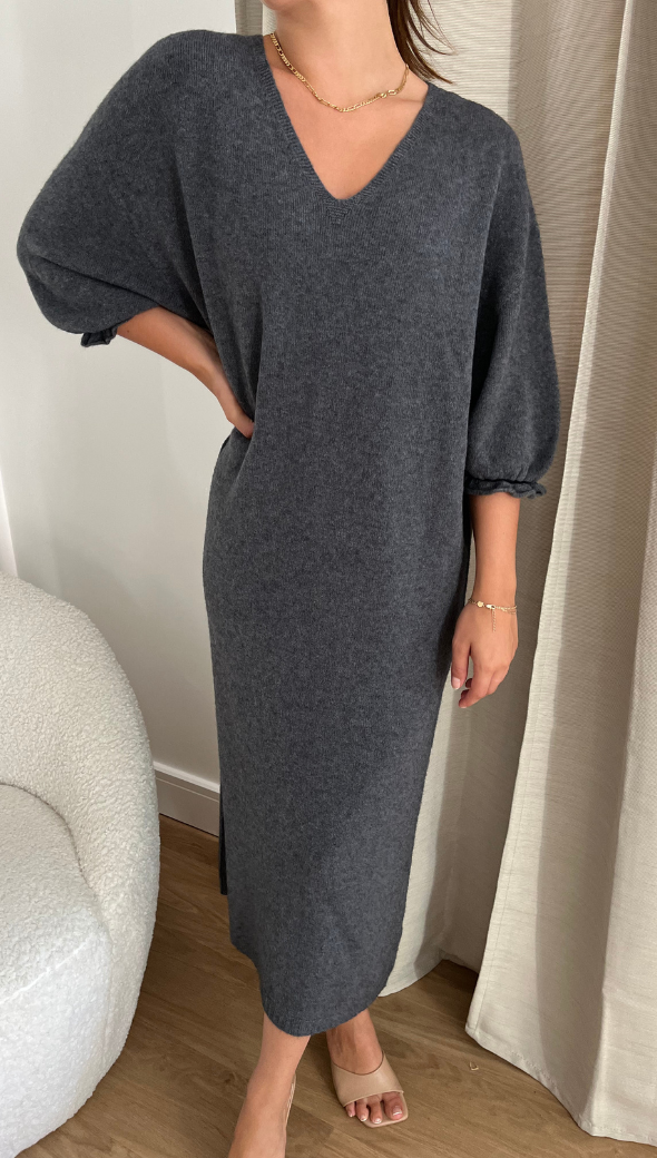 dark gray V-neck midi sweater dress with loose three-quarter sleeves, accessorized with a delicate gold necklace and bracelet