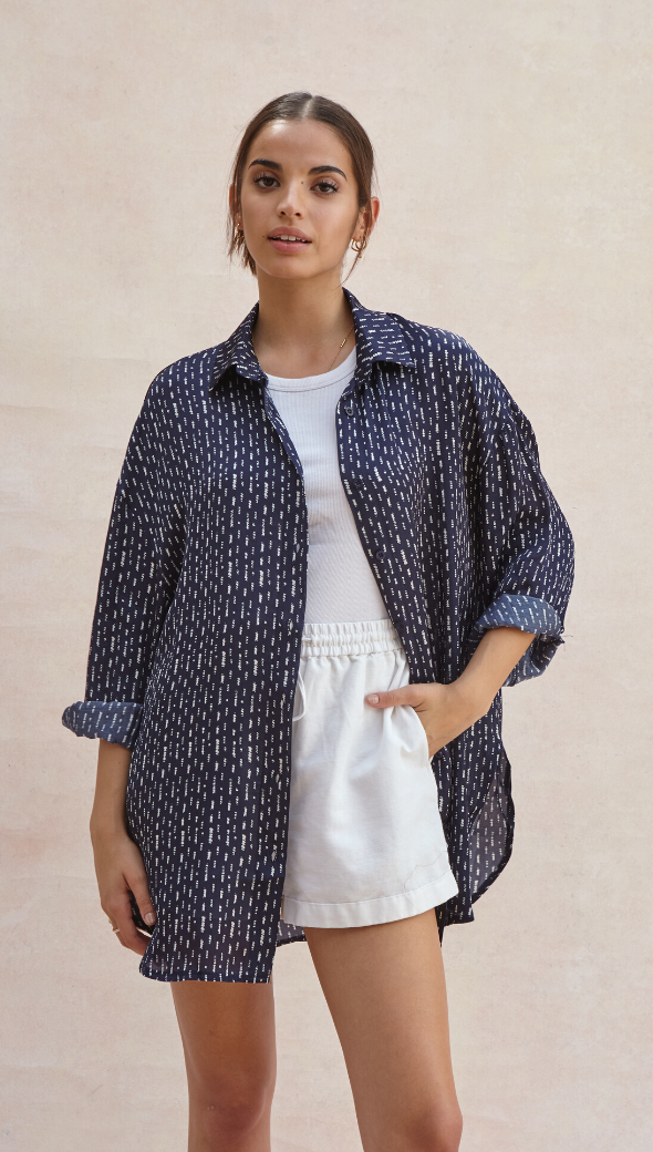 navy blue patterned button-up shirt over a white top, paired with white shorts